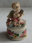 Porta Joia de resina sobreposto com figura de anjo sentado, ricamente decorado com motivos florais. Diam 6cm - alt. 11cm.