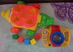 Lote com 2 brinquedos sendo Jacaré com peças de encaixe para desenvolver a criança com 31cm e máquina fotográfica de brinquedo com  18cm
