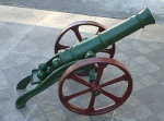Canhão de ferro fundido decorativo grande proporção, modelo Influencia século XIX, laqueado no padrão verde folha e vermelho, acompanha 4 bolas na plataforma de recarga. medida Altura 50cm x  95cm de comprimento x 50cm de largura.
