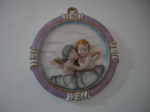 Prato circular de parede representando querubins em alto relevo, com rica policromia Diam. 17 cm