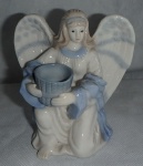 Escultura de Porcelana  ao gosto Lladro - Anjo de porcelana na tonalidade branca e azul, ajoelhado segurando cesto de vime. em perfeito estado, manufatura não identificada. Med. 9cm x 11cm.
