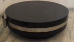 Anos 70, mesa de centro ou lateral, laqueada na cor preta, circundada por espessa fita em metal cromado, detalhe de arremate em curvas. Medindo 90 cm de diâmetro e 30 cm de altura.