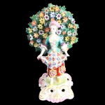 Escultura em porcelana representando dama na árvore. Inglaterra. 19 cm de altura. (Com bicados)