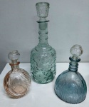 Conjunto de 3 licoreiras em vidro antigo trabalhadas , uma ( rosa menor ) apresenta discreta trinca interna. Medem: 33. 20 e 12 cm  (M)