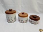 Lote de 3 potes em porcelana floral com tampa em madeira. Medindo 16cm; 12,5cm; 8,5cm de altura respectivamente.
