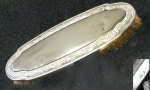 Antiga escova, 18x5,8cm, guarnecida em prata, contraste não identificado; na margem, friso de volutas em relevo, íntegra, sinais de manuseio, cerdas originais.