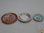 Lote de 3 pratos decorativos, sendo um em porcelana Noritake floral, um em porcelana oriental com gueixas e um em bronze esmaltado clossone floral. Medindo o maior 10 cm de diâmetro.
