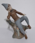 Figura de porcelana representando menino em descanso, em bom estado de conservação e medindo 25 cm d