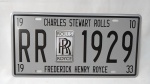 2. Bela placa de metal com emblema da ROLLS ROYCE. Curiosidade: originalmente, os dois `R` do logotipo eram estampados em vermelho, mas após a morte de seus fundadores, Charles Rolls (1910) e Frederick Royce (1933), as letras passaram a ser grafadas em preto, em sinal de luto, respeito e reverência. A placa mede 30x15cm. <br>