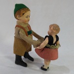 Brinquedo antigo Schuco - Menino levantando uma menina a corda. Fabricado na década de 40. O menino tem rosto e corpo metálico e a menina de celulóide, tem um rachado na cabeça da menina. Não acompanha chave de corda