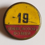 Antigo CRACHÁ em metal da General Motors do Brasil, com o número 19. Mede 05 cm de diâmetro.