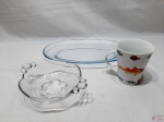 Lote composto de travessa oval rasa em vidro, petisqueira bowl em vidro e caneca em porcelana com peixes. Medindo a travessa 33,5cm x 22,5cm.