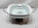 Penela em porcelana com tampa de vidro com rechaud e fogareiro em aço. Medindo a panela 24cm x 20,5cm x 6,5cm de altura.