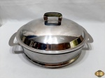 Pirex redondo em vidro Colorex com suporte e tampa em aço inox Platinox. Medindo 26cm de diâmetro x 7,5cm de altura.