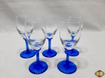 Jogo de 4 taças de licor em cristal incolor com pé azul cobalto. Medindo 11,5cm de altura. Uma delas com um leve bicado, conforme ilustra na foto.