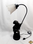 Abajur com escultura de casal em resina e cúpula em vidro fosco. Medindo 56,5cm de altura. A cúpula possui uma pequena perda em uma das pontas.
