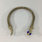 Elegante pulseira em metal amarelo, rico em detalhes, no formato de cobra. Olhos rematados em pedra semi preciosa azul. Exemplar em excelente estado. Dimensões: 26 cm.