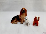 Lote de 3 enfeites na forma de cachorro, sendo 2 em porcelana e 1 em resina. Medindo o maior 13,5cm de comprimento x 12,5cm de altura.