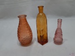 Lote de 3 garrafas decorativas em vidro colorido moldado, podendo ser usadas como floreiras. Medindo a maior 17,5cm de altura.