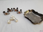 Lote diverso, composto de 5 dados, 4 argolas de guardanapos em aço com naipes e petisqueira em estanho. Medindo a petisqueira 14cm x 9,5cm x 2,5cm de altura.