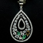 Majestoso Pingente em prata de lei teor 925 espessurada a ouro branco , design moderno exclusivo com bela Cravação de Esmeraldas , Turmalina , rico trabalho e incrustação de zirconias , totalizando 18.15 cts . Perfeito estado de conservação . mede 3,4 x 2,0 cm . Origem Nigéria e Zâmbia .