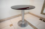 ARTZZI- Elegante mesa de canto com base de metal prateado e tampo em vidro fumê fosco, trabalhada pela renomada marca Artzzi, mede 65cm (alt) e 70cm (diâm.). Excelente estado de conservação. (ENVIO FACILITADO SP , RJ E MG ) .