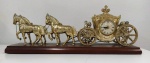 Relógio de mesa em formato de carruagem em antimônio pintado de dourado sobre base de madeira  . Não testado . Mede: 54x 20  cm