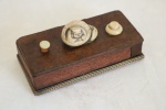 Antiga caixa interruptor em madeira nobre folheada com rádica, aplicada sobre lea NETZUKÉ de marfim, representando figura, guarnição em metal dourado. Med. 3x12,5x6 cm.