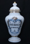 Pote de farmácia no feitio de balaústre em demi cristal opalinado em tom branco leitoso com ricos frisos dourados. Identificador ("THERIACA ANDROMAC") em negro, emoldurado com arabescos também em dourado. Alt.: 32 cm. (Em função da fragilidade, recomendo o envio em caixa de isopor).