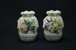 PORCELANA - Lote de 2 pequenas floreiras em porcelana decoradas com aplicações de flores e folhagens (faltas) e frisos dourados. Alt. 11 cm.