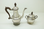 METAL ESPESSURADA A PRATA - Parte de jogo de chá, composto de: Bule de café e açucareiro em metal espessurado a prata, decoração perolada com alça e puxadores em jacarandá torneado. Med. 31x25 cm e 19x17 cm.