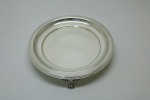 METAL ESPESSURADA A PRATA - Salva em metal espessurado a prata, estilo Dona Maria, lavrada e cinzelada, elevada sobre 3 pés em garras. Med. 3,5x20 cm.