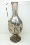 Antiga e grande jarra em cobre martelado, alça cinzelada, apresenta resquícios de banho de prata. Alt. 61 cm. Apresenta amassados e e rachadura no gargalo. Peso aproximadamente 3 kg.