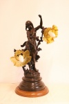 Magnífica luminária de mesa ART NOVEAU, para duas lâmpadas, confeccionada em petit bronze francês patinado, apresentando riquíssimo trabalho a cinzel, representando "ninfa com ramos de flor". Base circular. Cúpulas em vidro moldado satiné, bicolor. Alt. 70 cm.