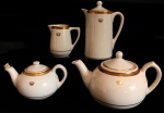 PORCELANA - Lote de conjunto em porcelana em tom marfim com bordas ricamente douradas e gravadas com delicada coroa, composto de: bule de chá, bule de café, leiteira, chaleira. Maior 19 cm e menor 9 cm.