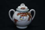 PORCELANA - Delicado açucareiro em porcelana oriental, policromada com decoração de flores, pássaro, com alças laterais. Med. 15x16 cm. Marcada no fundo.