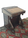 Davenport em madeira nobre, laterais uma com 4 gavetas e outra simulando 4 gavetas, bancada oblíqua forrada com couro pirogravado (no estado), tampo flexível com dobradiças, interior com escaninhos e 3 gavetinhas, 2 colunas torneadas em folha de acanto, pés em pitanga. Estilo inglês. Med. 82x66x63 cm.