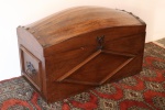 Antigo e grande baú em madeira nobre, decorado com molduras, tampa feita a partir de barril, tachões em bronze. Med. 63x102x52 cm. Interior forrado.