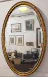 Espelho de parede, de madeira dourada e espelho bisotê. Medidas aproximadas: 60 cm x 88 cm de altura.