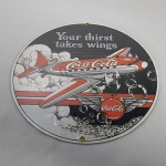 Placa Esmaltada da Coca-cola com Avião, lacrada, fabricada pela Ande Rooney - Estados Unidos, conhecida como placa de porcelana. Mede 25,5 centímetros de diâmetro, com os dizeres YOUR THIRST TAKES WINGS