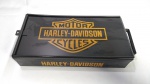 Caixa Esmaltada e em Relevo das Motocicletas HARLEY-DAVIDSON. Mede aproximadamente 31 X 16,5 X 6 centímetros, sem contar a alça. Na lateral existe trava para cadeado.