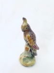 Escultura em porcelana representando pássaro sobre tronco. Med. 12 cm. 