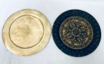Dois pratos em metal, sendo um deles decorado com arabescos e o outro com a borda cinzelada. Med. 29 cm. (cada)