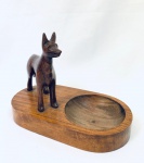 Objeto decorativo em madeira ornado com escultura representando cachorro e parte redonda ao lado. Med. 16x22 cm. 