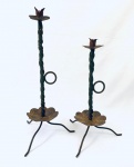 Dois castiçais em ferro retorcido com pega redonda e três pés. Med. 48 cm. / 38 cm. 