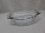 Travessa oval com tampa em vidro temperado. Medindo a travessa 34cm x 21,5cm x  9,5cm de altura. Com bicado na borda da travessa e na tampa.