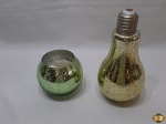 Lote composto de garrafa na forma de lâmpada e castiçal com vela bolinha, peças em vidro pintado. Medindo a garrafa 22,5cm de altura.