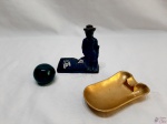 Lote composto de enfeite na forma de guarda em ferro, cinzeiro em bronze e peso de papel em vidro na forma de bola. Medindo o cinzeiro 11,5cm x 7cm x 2cm de altura.