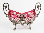 BACCARAT LAPIDAÇÃO COLBERT COM GUARNIÇÃO EM PRATA DE LEI. SUNTUOSO CENTRO DE MESA COM FEITIO NAVICULAR NA TONALIDADE RUBI E TRANSLÚCIDO. SUSTENTADO POR MAGNIFICA GUARNIÇÃO EM PRATA DE LEI DECORADA COM ESCUDELAS LAUREADAS E FOLHAS DE ACANTO. A GUARNIÇÃO EM PRATA DE LEI PESA APROXIMADAMENTE 1 KG. FRANÇA, INICIO DO SEC. XX. 38 CM DE COMPRIMENTO