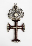 SUNTUOSA CRUZ DE COMENDADOR DA ORDEM DE NOSSO SENHOR JESUS CRISTO EM PRATA DE LEI COM RICA CRAVAÇÃO DE GRANADAS FORRADAS SIMULANDO RUBIS E MINAS NOVAS. RICA OURIVESSARIA SETECENTISTA DO BRASIL COLONIAL. AS GRANADAS SÃO LAPIDADAS EM BAGUETE E AS MINAS NOVAS LAPIDADAS COMO DIAMANTES.  DIFICILMENTE SE VERÁ EXEMPLAR EXECUTADO COM TAMANHA QUALIDADE, DIMENSÃO E RIQUEZA. NOS CRÉDITOS EXTRAS DESSE LOTE DUAS GRAVURAS DE DEBRET; UMA RETRATA UM DESEMBARGADOR DESCENDO DE CARRUAGEM CINGINDO A COMENDA E NA OUTRA OS GRAUS E VESTIMENTAS DOS TITULARES DA ORDEM NO BRASIL IMPERIAL. SEC. XVIII. 12,5 CM DE ALTURA.NOTA: A origem das ordens militares, criadas no século XII, está associada às cruzadas e à Reconquista cristã da Península Ibérica. Elas se caracterizavam como braços armados da cristandade. Seus cavaleiros deveriam seguir uma vida regrada pelas leis cristãs, assim como monges, com votos de castidade, pobreza e obediência. Mais tarde, elas serviram igualmente à expansão ibérica para os continentes africano, asiático e americano. A administração dessas ordens, denominada de Mestrado, que estava sob a responsabilidade da Igreja Católica, foi passada aos reis portugueses em duas Bulas: a primeira foi a do Papa João XXII, em 1319, quando os cavaleiros Templários foram extintos na Europa e, em substituição, foi criada a Ordem de Cristo em Portugal. A segunda foi a Bula do Papa Júlio III de 1551, quando mais duas ordens militares transformaram-se no braço armado da Coroa portuguesa: a Ordem de São Bento de Aviz, cuja criação data da fundação da monarquia portuguesa, e a Ordem de Santiago, criada em 1290. Desde a criação dessas ordens militares até o século XIX, muitas mudanças ocorreram. Várias reformas foram realizadas por diversos monarcas, antes, durante e depois da Unificação da Península Ibérica (1580-1640). As exigências para que um candidato fosse armado cavaleiro e que vigoraram por vários séculos - por exemplo, a exigência de sangue puro, sem mancha judia ou muçulmana, ou mancha mecânica na linhagem familiar - foram caindo ao passar dos séculos, sendo menos freqüentes no século XVIII, quando o número de dispensas aumentou muito. Outra mudança muito significativa foi a natureza dos serviços prestados e que eram recompensados com comendas. Se desde a origem das ordens os serviços eram predominantemente de natureza militar, no avançar dos séculos os serviços recompensados deixaram de ser apenas militares e muitos outros tipos de serviços passaram a ser recompensados, como no caso dos magistrados, daqueles que serviam ao rei ou atuavam no Estado. Esse é o motivo pelo qual alguns afirmam que as ordens militares propriamente ditas estavam em decadência já no século XVII, e, por isso, preferem adotar o termo ordens honoríficas em seu lugar, embora o termo militar não tenha saído de uso nas fontes. Contudo, é importante destacar que os serviços militares prestados não deixaram de ser recompensados com comendas, nem mesmo no século XIX. D. João e D. Pedro criaram diversas ordens honoríficas, para além das três Ordens Militares portuguesas, utilizando um instrumento que capitaneava os desejos de ascensão hierárquica e de distinção dos luso-brasileiros, com o intuito de angariarem os benefícios da vassalagem e da fidelidade. Tratava-se de um jogo cujos benefícios iam para os dois lados: a Coroa e o condecorado, pois, enquanto a primeira angariava serviços e fidelidade, o segundo angariava benefícios materiais e simbólicos. É notável que o instrumento das ordens tenha sido utilizado em dois momentos extremamente delicados do Império português e, depois, brasileiro: a transferência de uma corte ameaçada pela revolução e, posteriormente, a criação de um Império independente. No primeiro caso, D. João premiou seus fiéis vassalos que o acompanharam na mudança da sede do Império e que se mantiveram leais à Coroa, bem como os coloniais de cuja fortuna necessitava, visto a difícil situação pecuniária da mesma. No segundo caso, D. Pedro construía um novo Estado, que dependia da consolidação de uma elite política fiel e igualmente do apoio das fortunas luso-brasileiras e, por isso, utilizou-se dos recursos das ordens. Assim, as ordens constituíram-se em um instrumento tanto de construção de elites, quanto de apoio e suporte ao regime e aos monarcas, tornando-se um importante mecanismo de funcionamento do poder régio. Sua lógica atendia não somente à promoção da imagem real como benevolente, mas também aos desejos de distinção de todos, pois significava um presente real e uma demonstração de estima por parte do monarca, de maneira que o regime se sustentava no imaginário social que concebia a sociedade como uma pirâmide. Cavaleiros da Ordem de Cristo faziam parte da nobreza sem título da Colônia e do Império do Brasil. Até Dom João V a Ordem de Cristo era concedida mediante rigoroso exame do postulante, duas características eram fundamentais: Sangue Limpo (que significava não haver em sua linhagem precedente elementos com ascendência judaica, moura ou negra) e comprovar que pelo menos há três gerações não houve registro de mácula mecânica ou seja depender da subsistência por esforço braçal. A partir do séc. XVIII, sob o reinado de DOM JOSÉ I, e da filha DONA MARIA I para garantir a fidelidade dos vassalos na colônia foi preciso dispensar alguns critérios na concessão da ordem e com a vinda da Corte Portuguesa para o Brasil houve um afrouxamento sem precedentes desses critérios. Não foi tarefa fácil transformar a rude colônia em sede de reino e para aglutinar esses esforços Dom João VI passou a oferecer aos ricos proprietários de terra a possibilidade de ascender a categoria de Nobreza não Titulada com a concessão da Ordem de Cristo. Essa estratégia esbarrava em alguns problemas técnicos por assim dizer, difícil era quem não tivesse no Brasil miscigenação de sangue ou que não tivesse dado duro para chegar a condição de senhor. Havia ainda uma categoria de cidadãos abastados enriquecidos de forma escandalosa como o tráfico de escravos. Tudo isso fez com que a partir daí a Ordem de Cristo, ou os critérios para sua concessão, nunca mais fossem os mesmos no Brasil ou em Portugal. Embora a posição de senhor de engenho por si só já oferecesse status privilegiado e uma posição de destaque dentro do cenário colonial muitos senhores de engenho almejavam obter títulos de nobreza devido às vantagens que o ser nobre conferia aos titulados. Fazer parte da nobreza como membros das ordens militares, por exemplo, significava estar isento de impostos como o dízimo, o que interessava a muitos senhores de engenho e em contrapartida era uma das razões para a relutância da Coroa em conceder estas honras. Uma patente de oficial miliciano, assinada pelo rei, proporcionava aos senhores de terra não só a tão almejada distinção, mas também regalias que se caracterizavam como um estilo de vida peculiar da nobreza, que incluía ter serviçais à disposição, usar montaria, gozar de regalias, como obter autorização para celebrar missas no oratório da casa e demonstrar refinamento de maneira e de costumes, a fim de serem reconhecidos enquanto homens bons. Aos homens bons cabia também a escolha, entre o seu meio, dos eleitores que, por sua vez, elegeriam os vereadores, juízes ordinários, procuradores, escrivães, almotacés e outros cargos das câmaras municipais das Vilas. Com a Independência do Brasil também era premente garantir as alianças locais e fidelidade dos súditos do Império nascente além da instituição de uma nobreza que garantisse a ordem social necessária ao aparato imperial. Depois da Independência do Brasil, o imperador Dom Pedro I continuou sua autoridade inerente como a fonte de honras transmitida por seu pai, o rei Dom João VI de Portugal. O Dignatário da  Grão-Cruz utilizava, além do manto e da medalha, uma faixa relativa à sua Ordem. Os Comendadores utilizavam o manto e a medalha que pendia do pescoço em uma fita de cetim. As medalhas utilizadas pelos Grão-Cruzes e Comendadores eram maiores e mais luxuosas que as dos Cavaleiros, sendo que estes últimos poderiam usar apenas a medalha e o manto, sem nenhuma faixa. O manto das três gradações, por sua vez, recebia um bordado indicativo do pertencimento à Ordem. Os bordados dos Grão Cruzes e dos Comendadores recebia um coração, como signo distintivo de sua posição, o que era proibido aos Cavaleiros. Conforme a descrição de Debret acerca dos mantos de gala da Ordem de Cristo é possível obter uma melhor visualização: O uniforme de gala dos cavaleiros de Cristo nas cerimônias religiosas constitui-se unicamente do manto da ordem com o crachá do lado esquerdo do peito; essa condecoração compõe-se de uma grande cruz branca, muito estreita, colocada no campo vermelho de outra mais larga de metal. O conjunto é cercado de raios de prata e encimado por um coração envolvido numa coroa de espinhos com uma pequena cruz vermelha. Este acessório pertence somente aos dignitários. O manto, fechado na frente por alamares, desce apenas até o estômago, deixando de fora a metade dos braços. Embora de fazenda extremamente leve, pois é feito de crepe branco, usa-se para maior comodidade toda a parte inferior enrolada sobre o peito com uma cinta de algodão branco (cordão) cujas enormes bordas pendem na frente. Toda essa passamanaria é cuidadosamente trabalhada. http://www.snh2011.anpuh.org/resources/anais/14/1307136341_ARQUIVO_TextoAnpuh2011.pdf